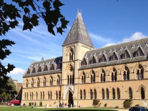 Image of museum of natural history, tall slate coloured roof against a bright blue sky